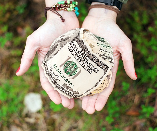 Balled $100 bills in a woman's hands indicating it's a gift.